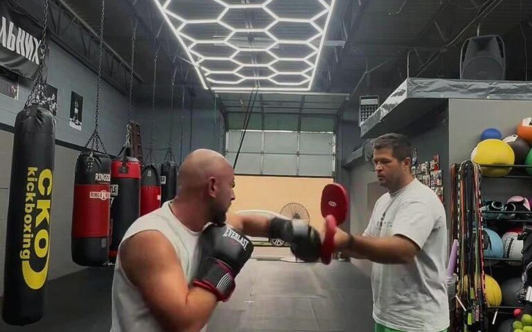 Pad work with the coach under the gym's honeycomb lights