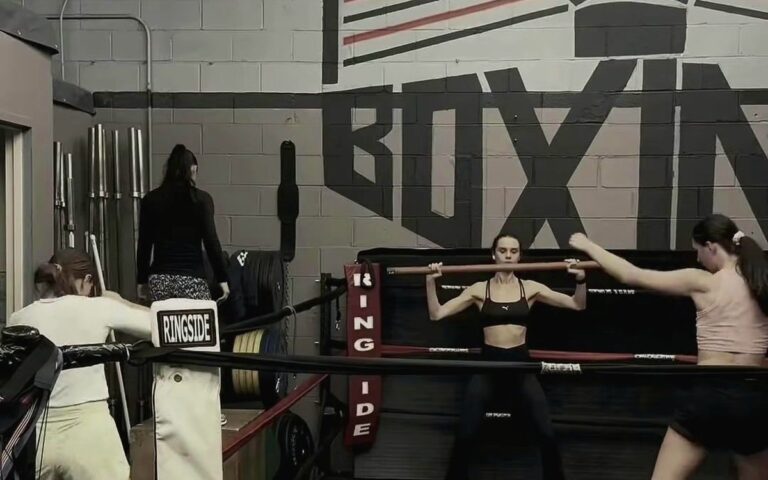 Women's group training in the ring under the BOXING mural