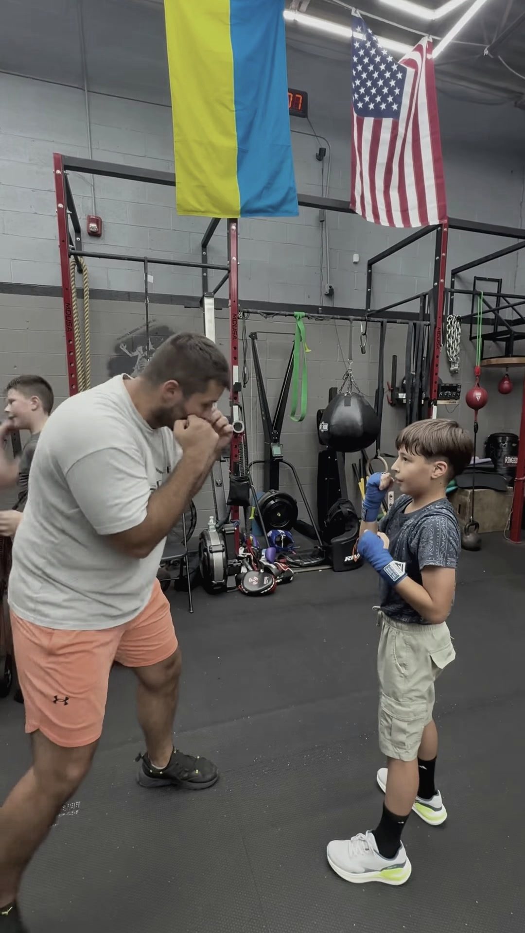 Coach showing guard position to a young boxer under the Ukrainian and US flags