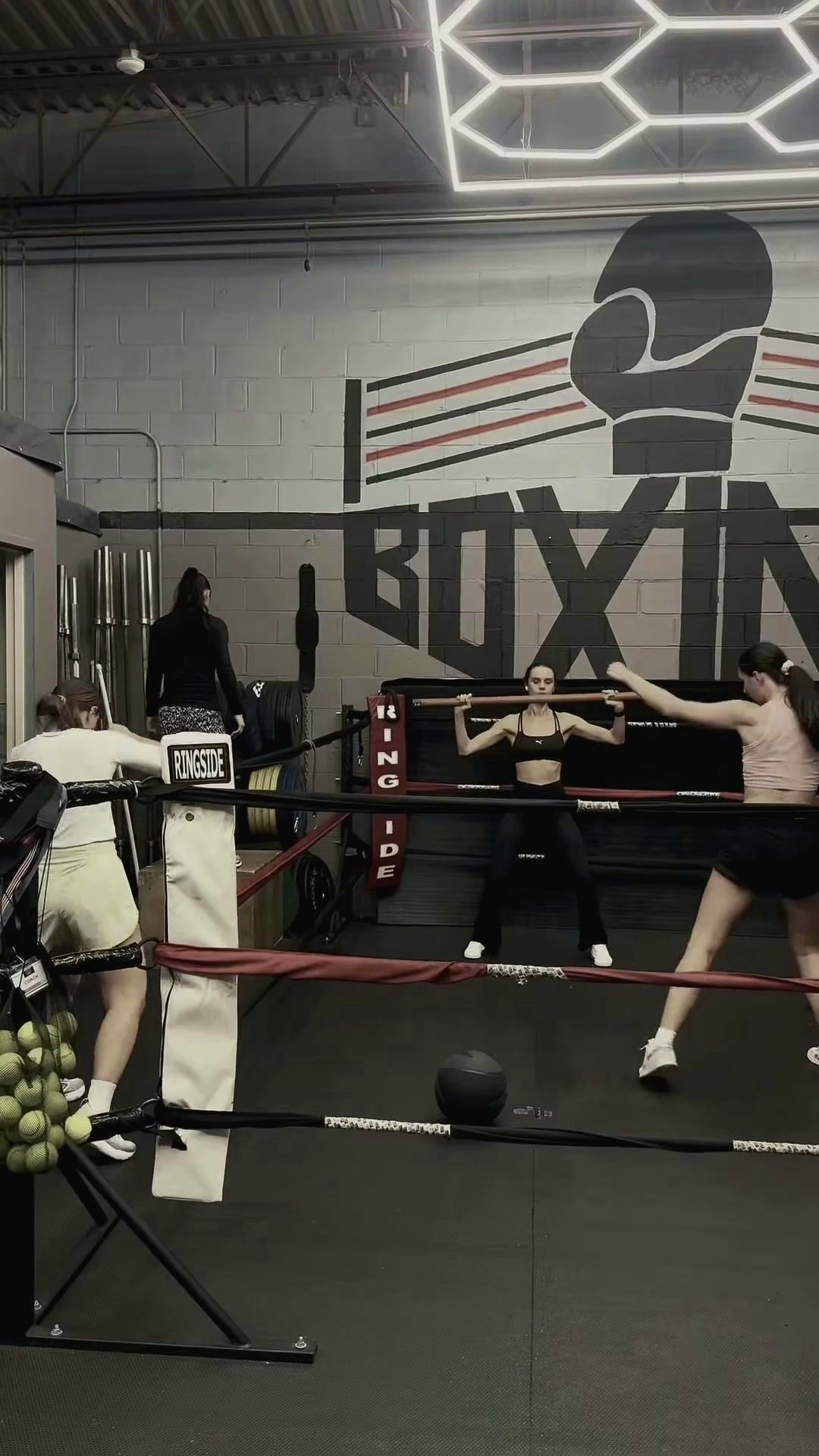 Women's class working in the ring under the BOXING mural