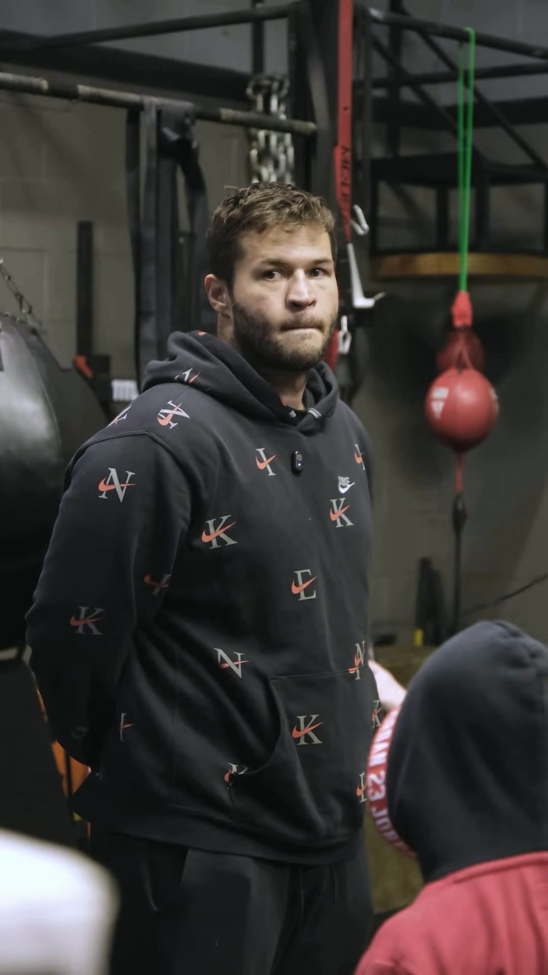 Robert Zhmurko in his gym, looking into the camera, a red double-end bag behind his shoulder
