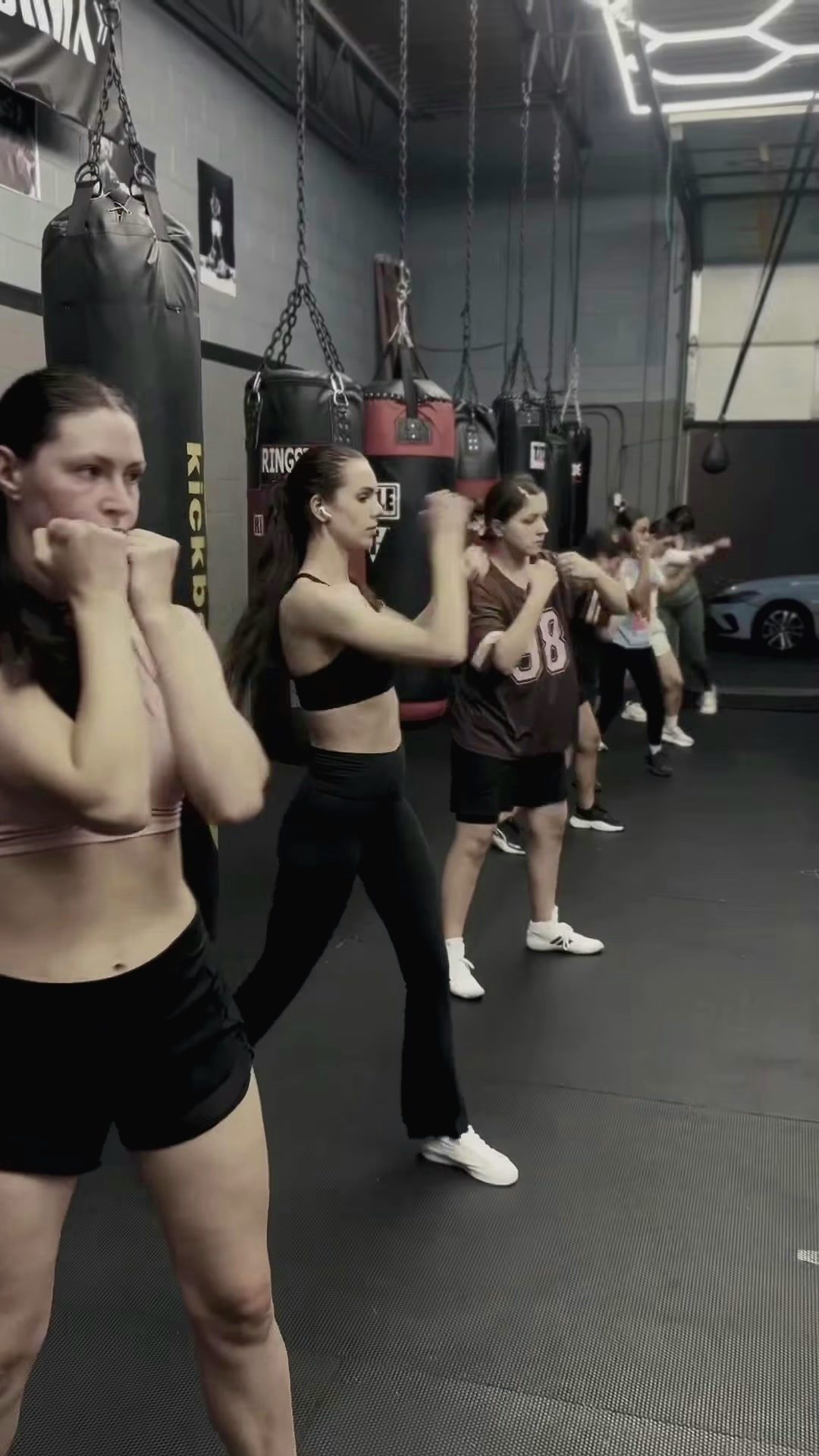 Women's group holding a boxing stance at the heavy bags